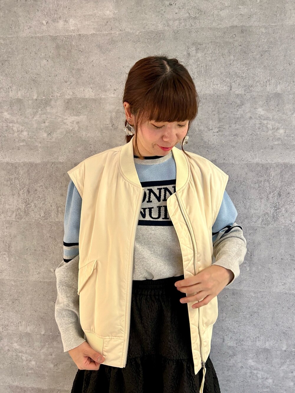 ホワイト系のスニーカー、ブラック系のスカート、イエロー系のトートバッグを着用したレディースの冬コーディネートの2枚目の写真