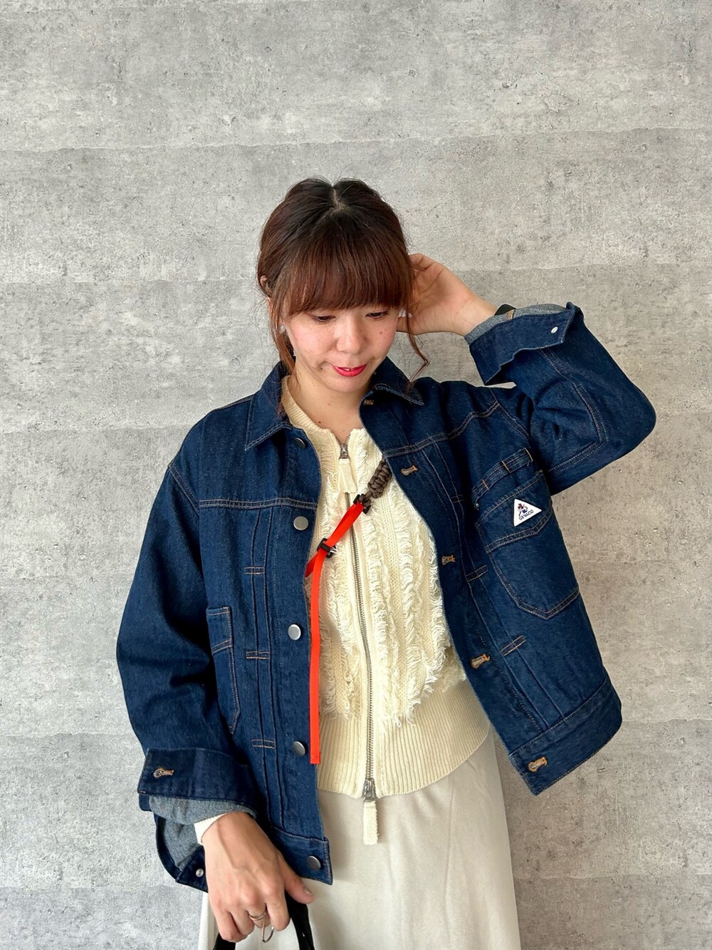 ベージュ系のスカート、ホワイト系のカーディガン/ボレロ、ブルー系のデニムジャケットを着用したレディースの秋コーディネートの2枚目の写真