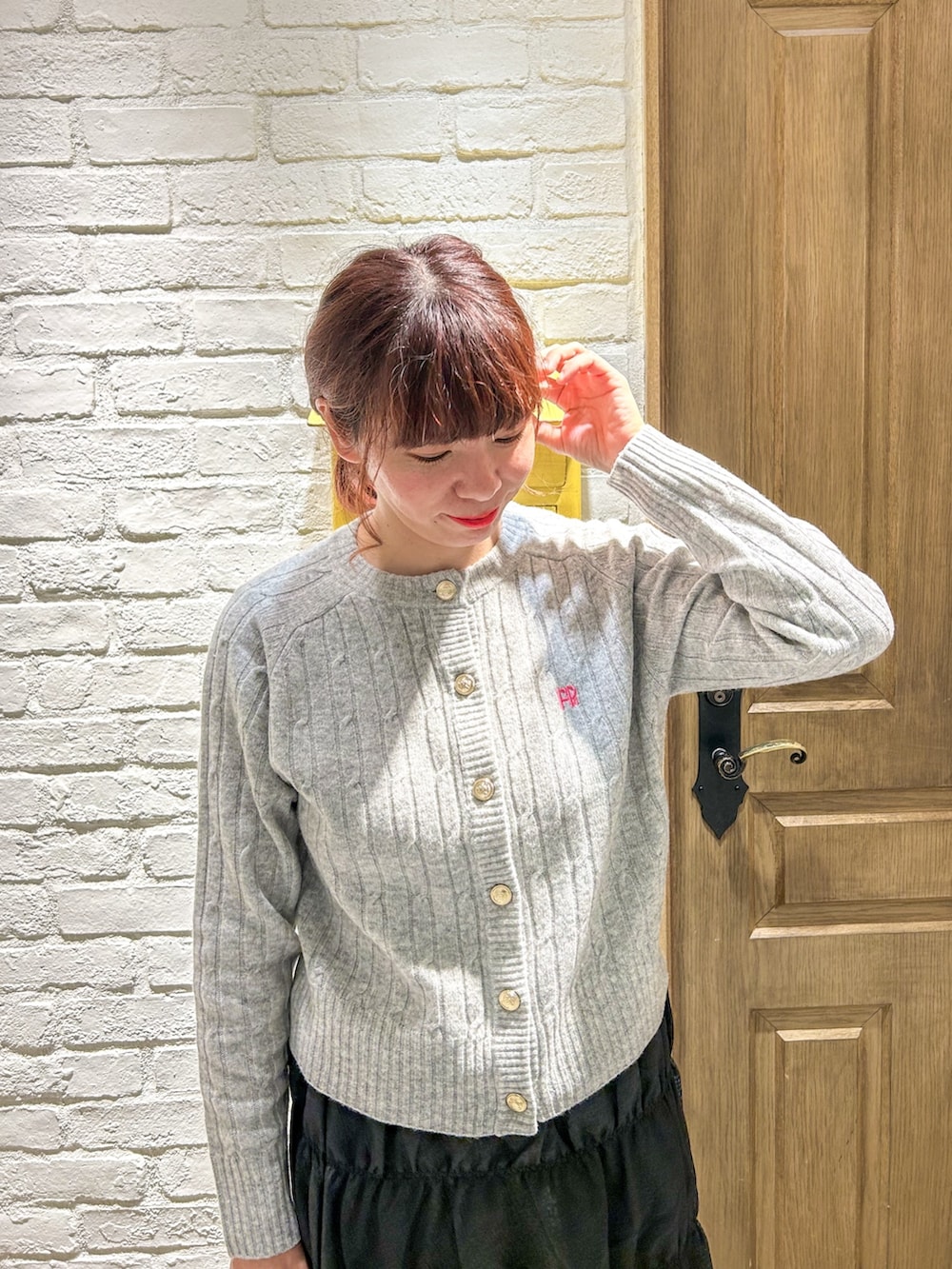 グレー系のカーディガン/ボレロ、ブラック系のスカート、グレー系のトートバッグを着用したレディースの秋コーディネートの2枚目の写真