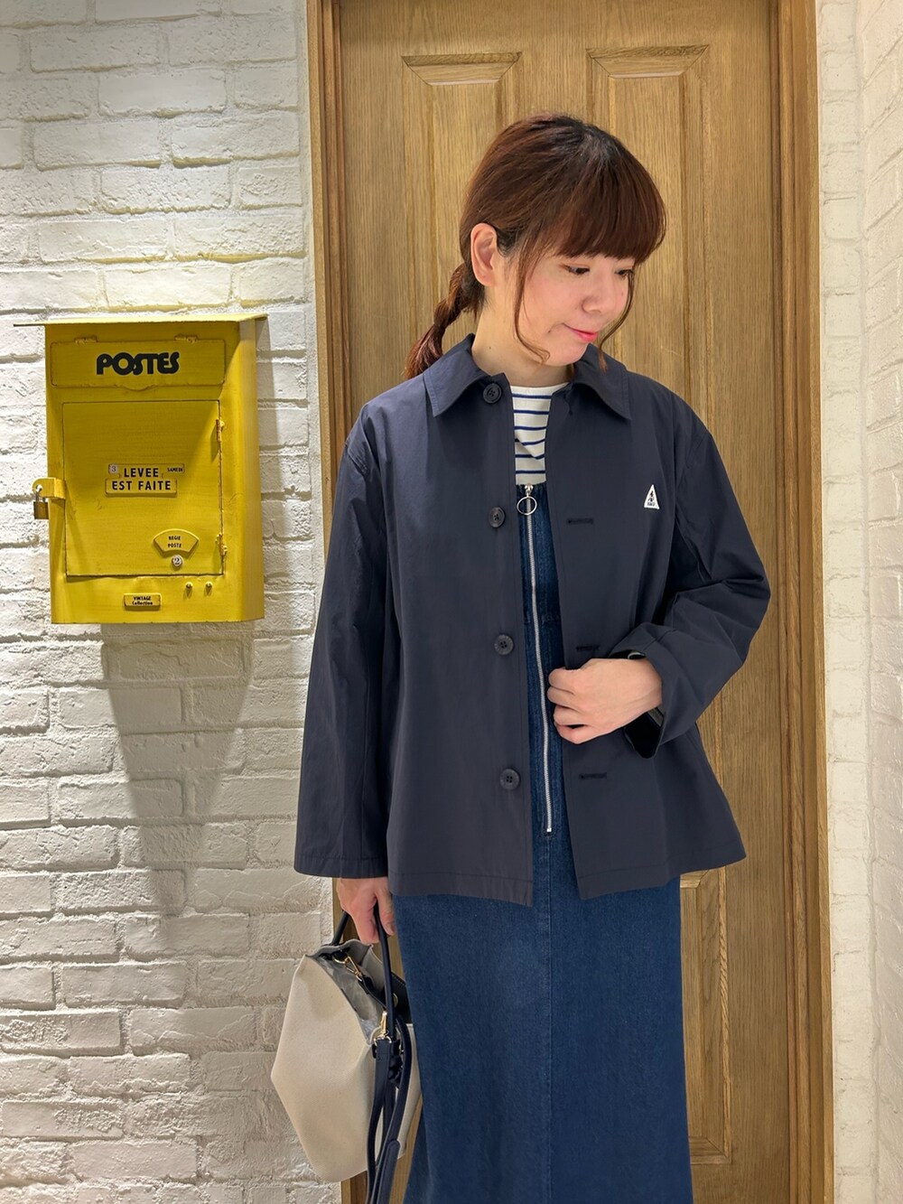 ブルー系のブルゾン、ブルー系のTシャツ/カットソー、ブラック系のジャンパースカートを着用したレディースの春コーディネートの2枚目の写真