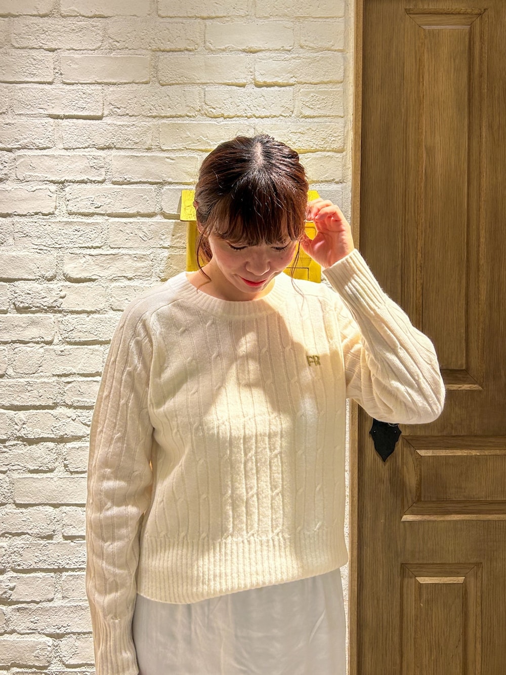 グレー系のトートバッグ、ホワイト系のニット/セーター、シルバー系のスカートを着用したレディースの秋コーディネートの2枚目の写真