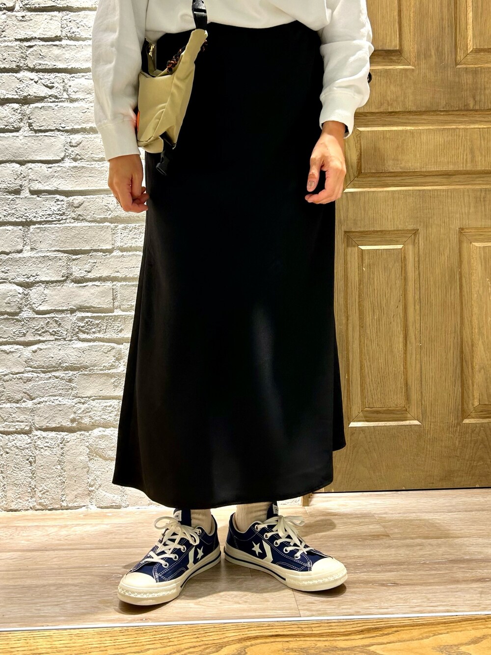 ブラック系のスカート、ベージュ系のショルダーバッグ、ホワイト系のスウェットを着用したレディースの秋コーディネートの3枚目の写真