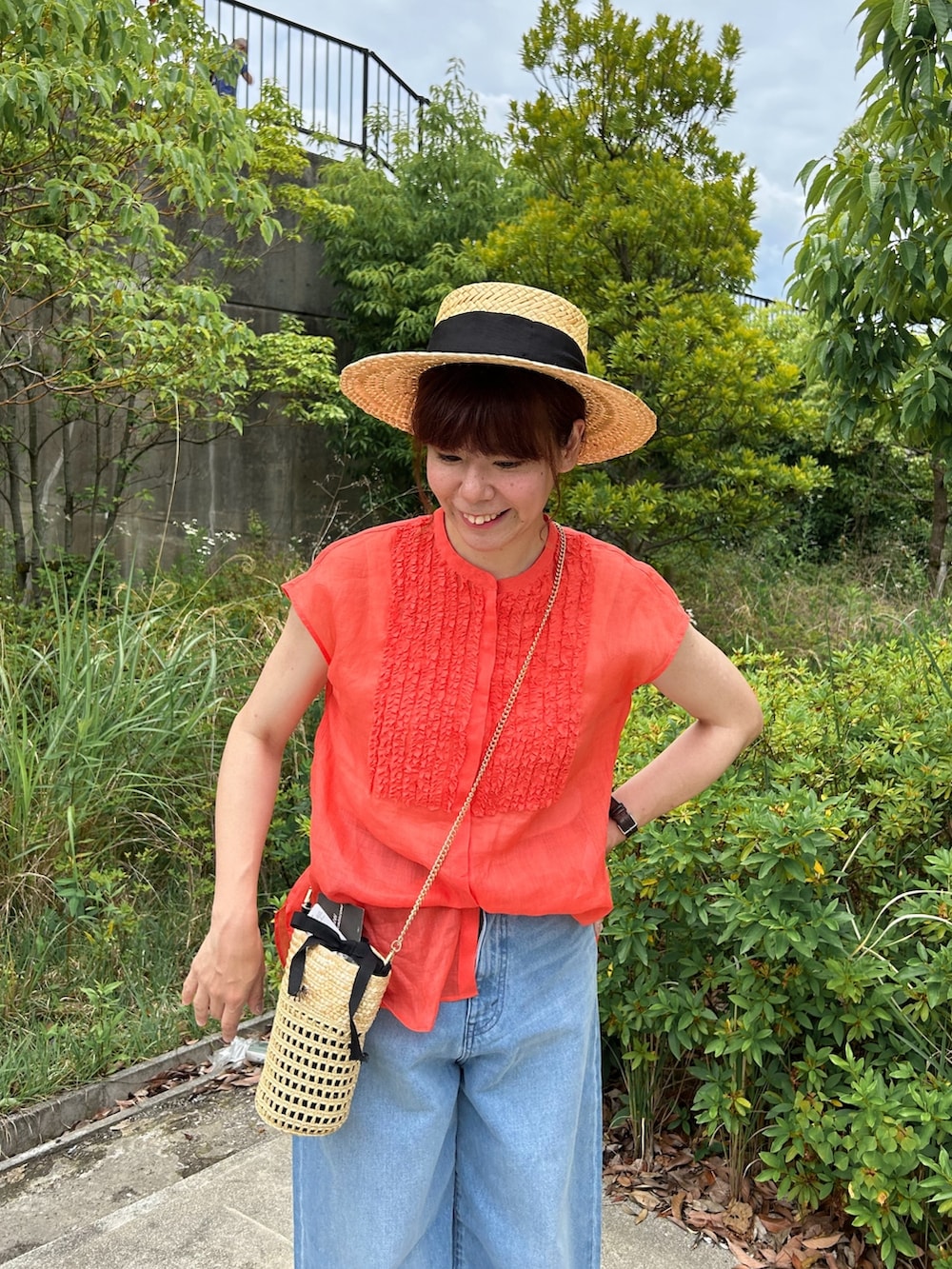 ブルー系のデニムパンツ、ベージュ系のかごバッグ、ブラック系のサンダルを着用したレディースの夏コーディネートの3枚目の写真