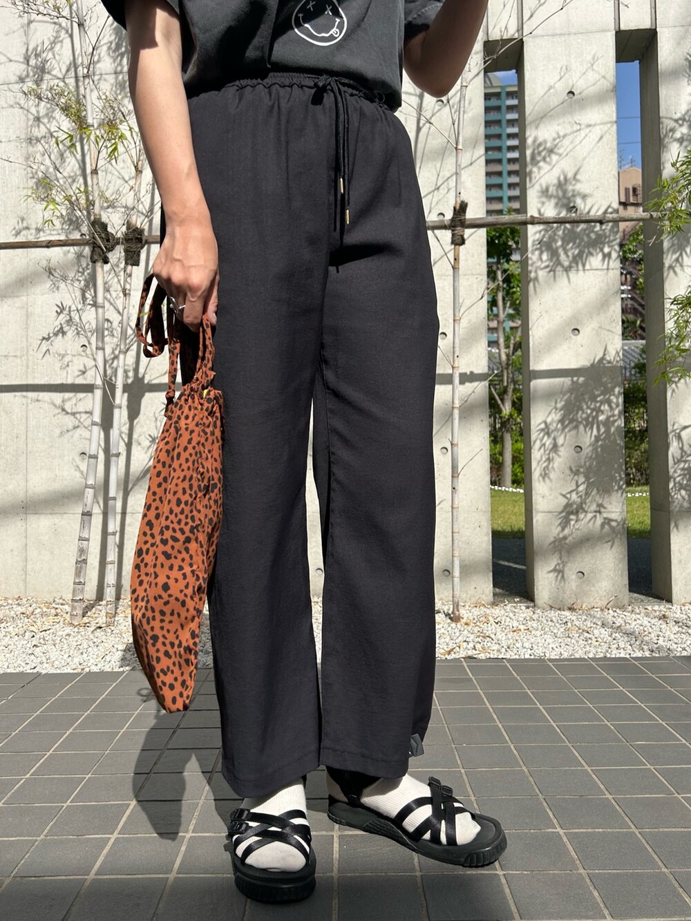 グレー系のTシャツ/カットソー、ブラック系のスラックス、ベージュ系のトートバッグを着用したレディースの春コーディネートの3枚目の写真