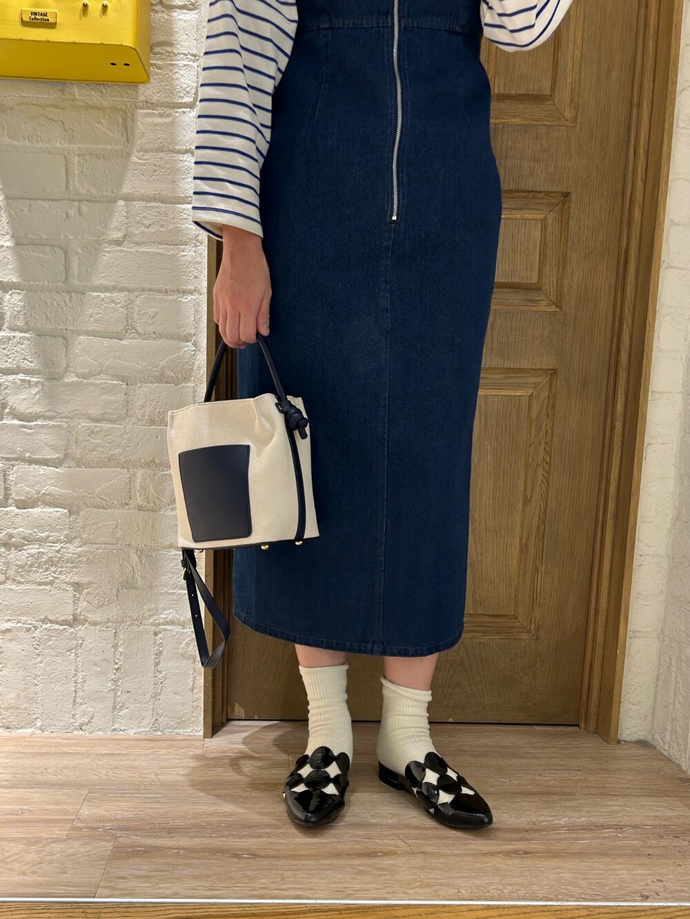 ブルー系のTシャツ/カットソー、ブラック系のジャンパースカート、イエロー系のトートバッグを着用したレディースの春コーディネートの3枚目の写真