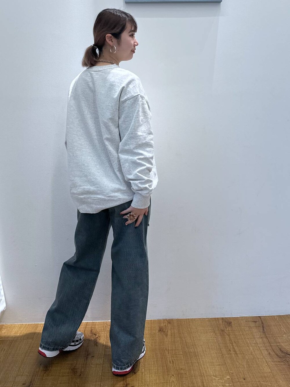 グレー系のスウェット、ブルー系のデニムパンツを着用したレディースの春コーディネートの3枚目の写真