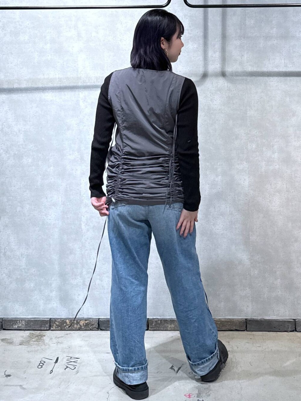 グレー系のワンピース、ブラック系のニット/セーター、ブルー系のデニムパンツを着用したレディースの冬コーディネートの3枚目の写真