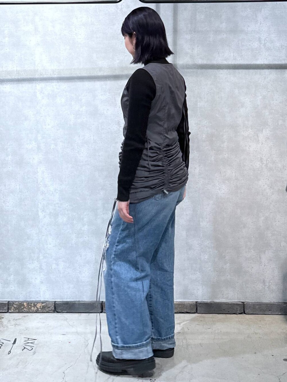グレー系のワンピース、ブラック系のニット/セーター、ブルー系のデニムパンツを着用したレディースの冬コーディネートの2枚目の写真