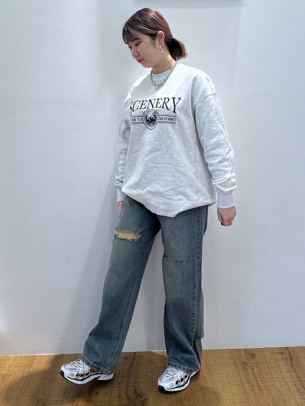 グレー系のスウェット、ブルー系のデニムパンツを着用したレディースの春コーディネートの2枚目の写真