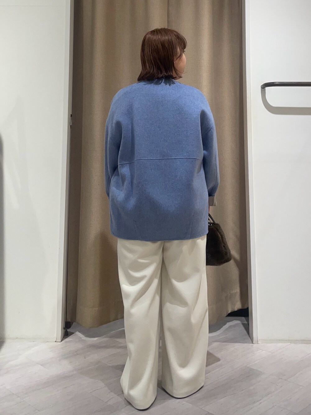 ブルー系のノーカラージャケット、ホワイト系のその他パンツ、ブラウン系のトートバッグを着用したレディースの秋コーディネートの2枚目の写真