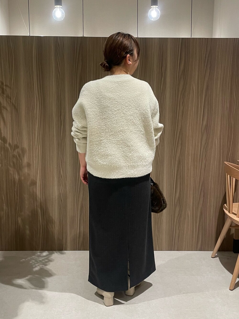 ホワイト系のニット/セーター、グレー系のスカート、ブラウン系のトートバッグを着用したレディースの秋コーディネートの2枚目の写真