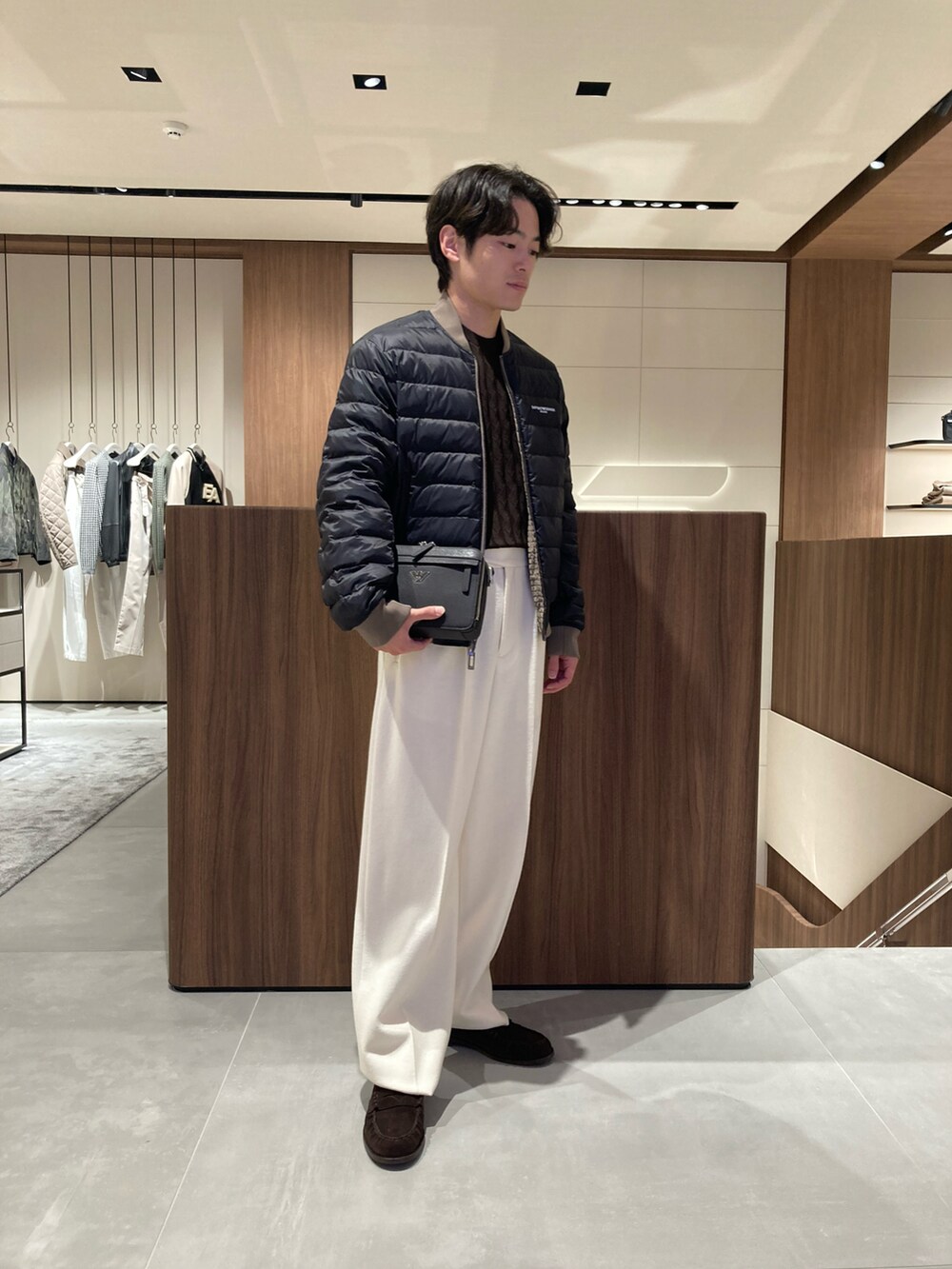 ブラウン系のダウンジャケット/コート、ブラック系のローファー、ブラウン系のニット/セーターを着用したメンズの秋コーディネートの2枚目の写真