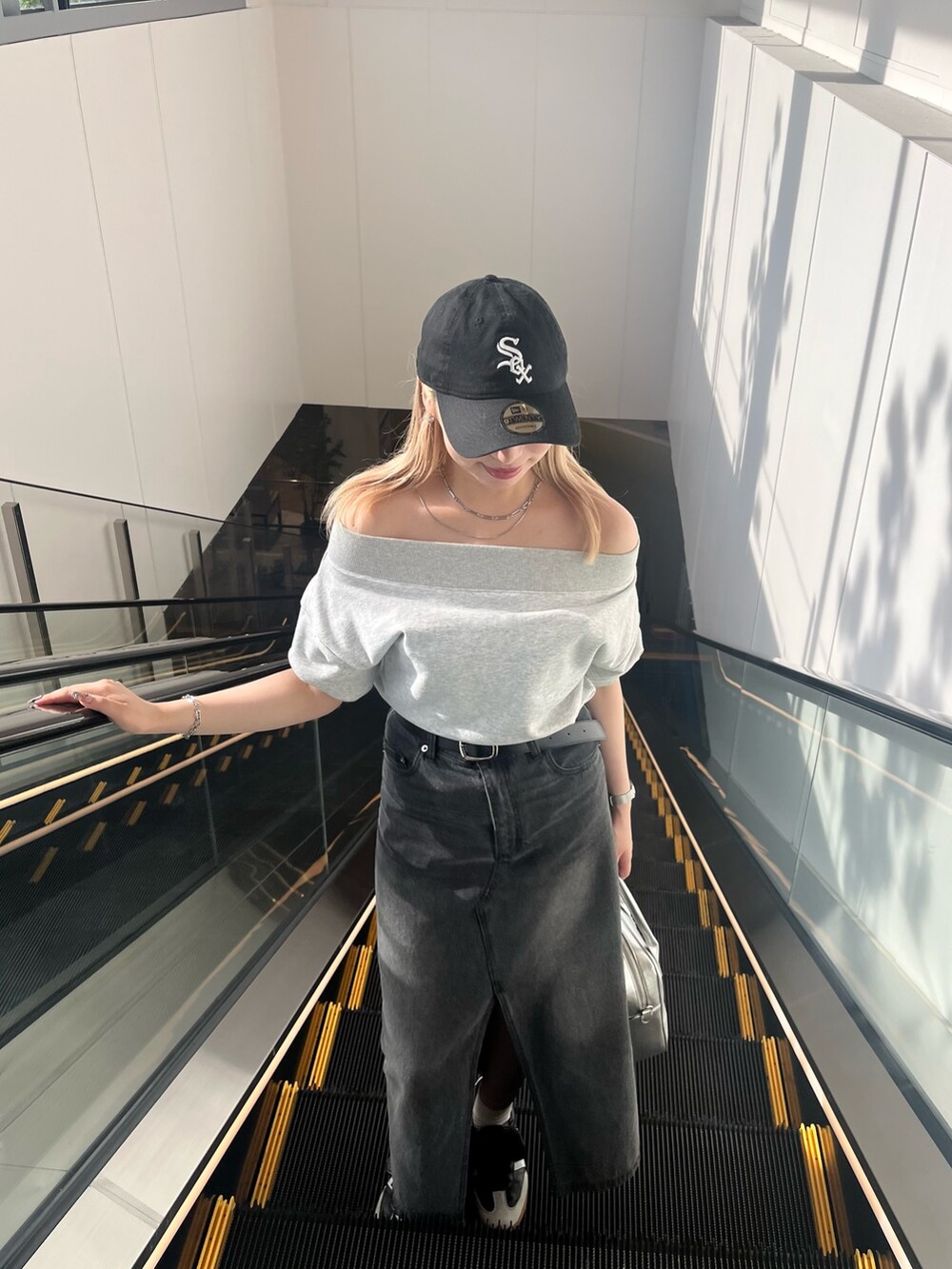 グレー系のスウェット、ブラック系のデニムスカート、ブラック系のベルトを着用したレディースの夏コーディネートの2枚目の写真