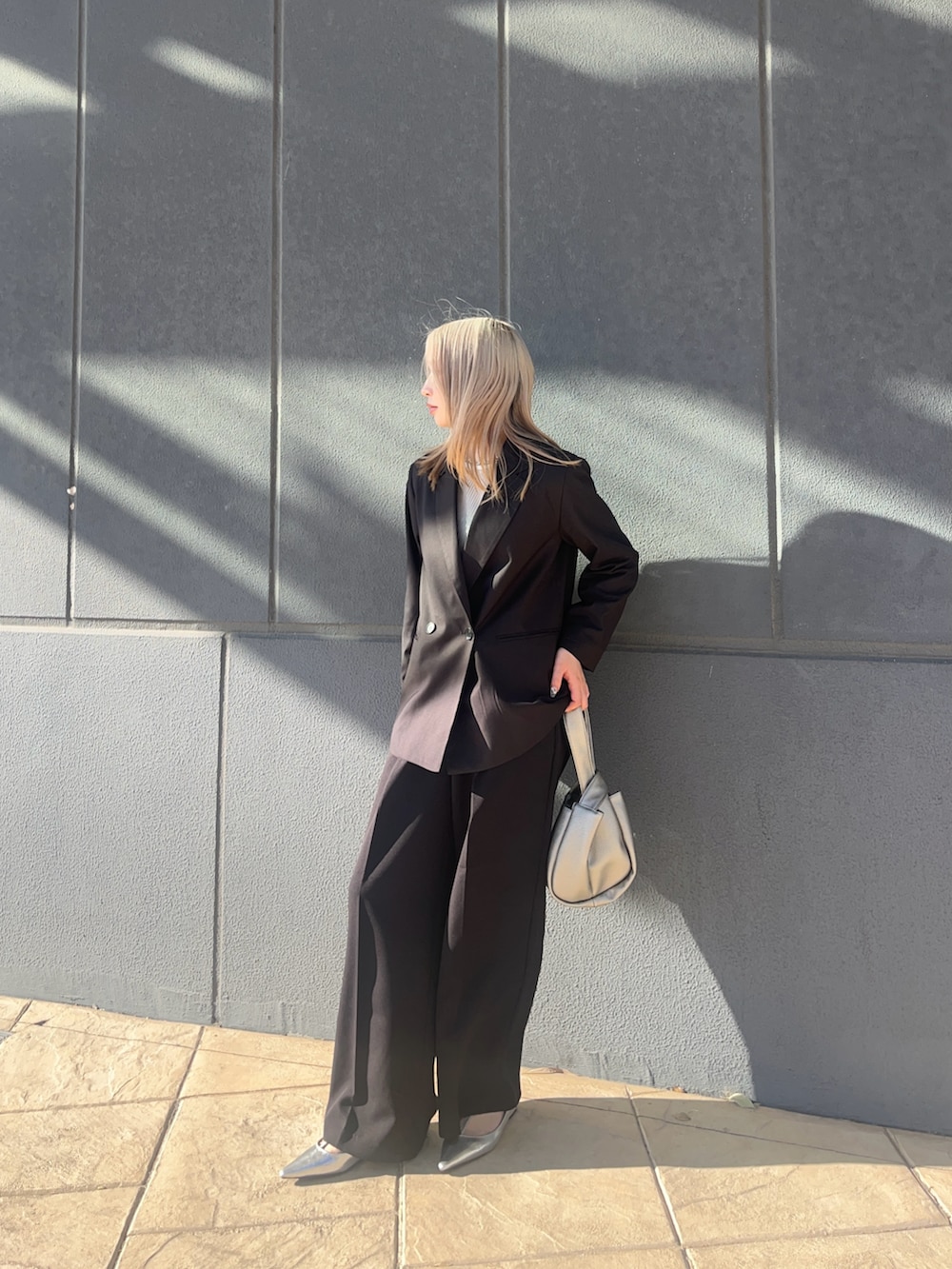 ブラック系のテーラードジャケット、ブラック系のスラックス、シルバー系のハンドバッグを着用したレディースの冬コーディネートの2枚目の写真