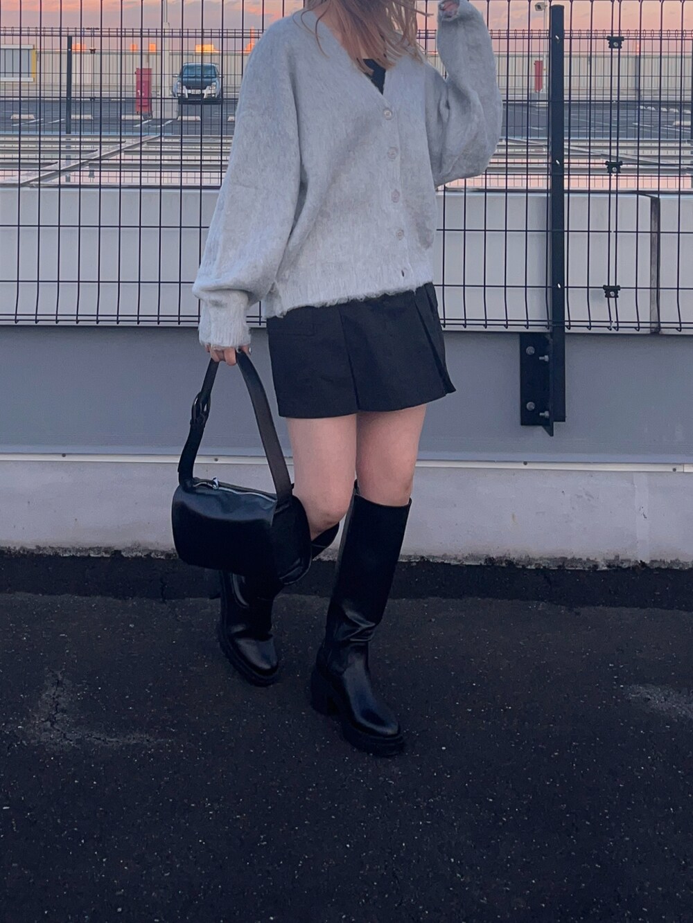 ホワイト系のカーディガン/ボレロ、ブラック系のブーツ、ブラック系のドラムバッグを着用したレディースの冬コーディネートの3枚目の写真