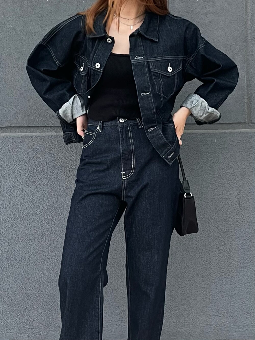 ブルー系のデニムジャケット、ブルー系のデニムパンツ、ブラック系のハンドバッグを着用したレディースの秋コーディネートの3枚目の写真