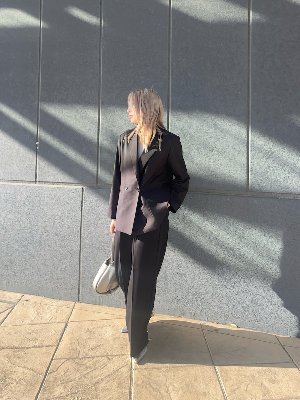 ブラック系のテーラードジャケット、ブラック系のスラックス、シルバー系のハンドバッグを着用したレディースの冬コーディネートの4枚目の写真