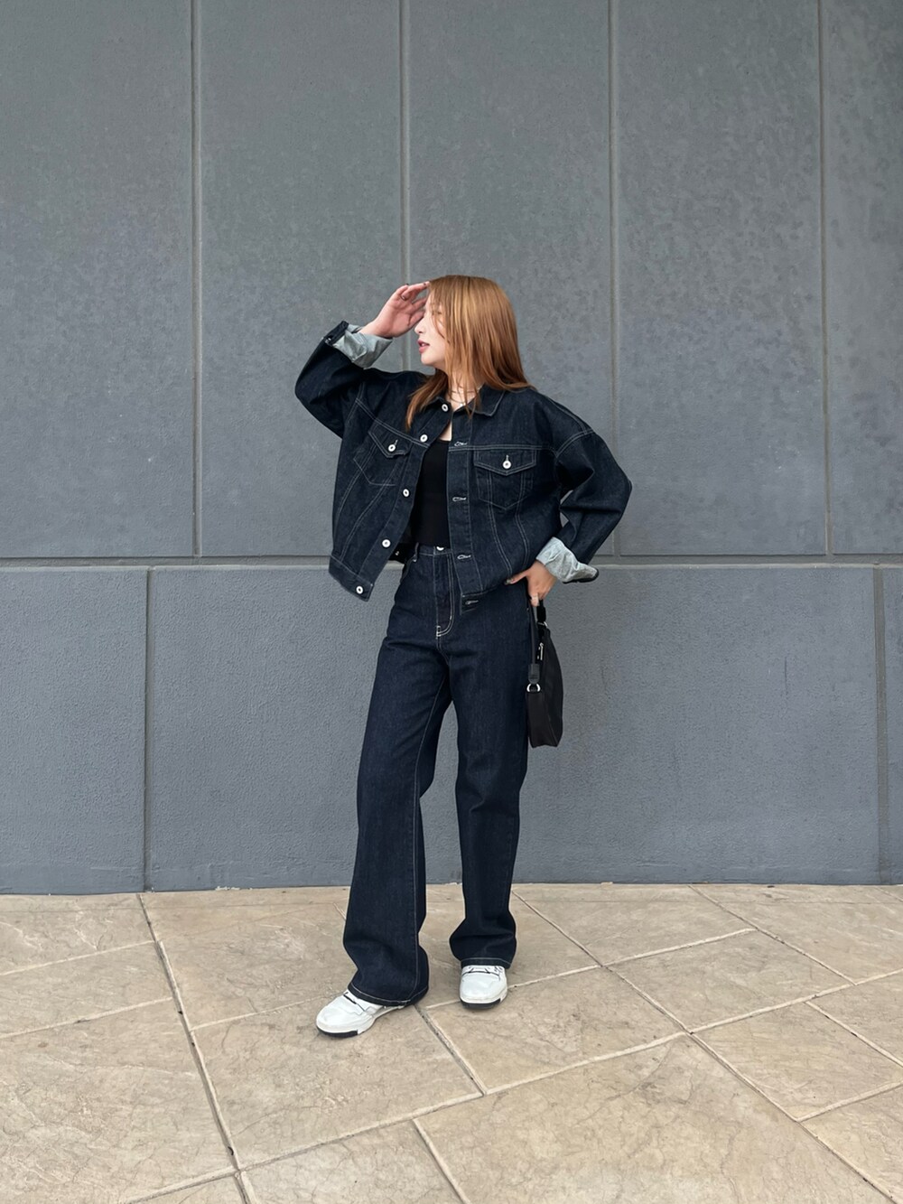 ブルー系のデニムジャケット、ブルー系のデニムパンツ、ブラック系のハンドバッグを着用したレディースの秋コーディネートの2枚目の写真