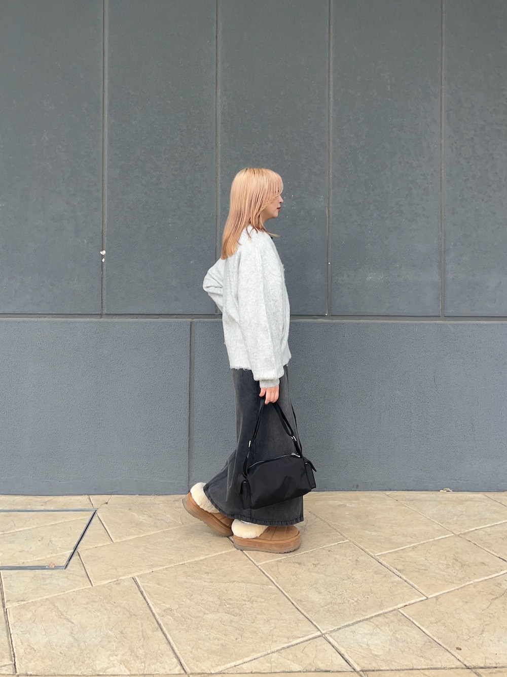 ホワイト系のカーディガン/ボレロ、ブラック系のデニムスカート、ブラック系のショルダーバッグを着用したレディースの冬コーディネートの3枚目の写真