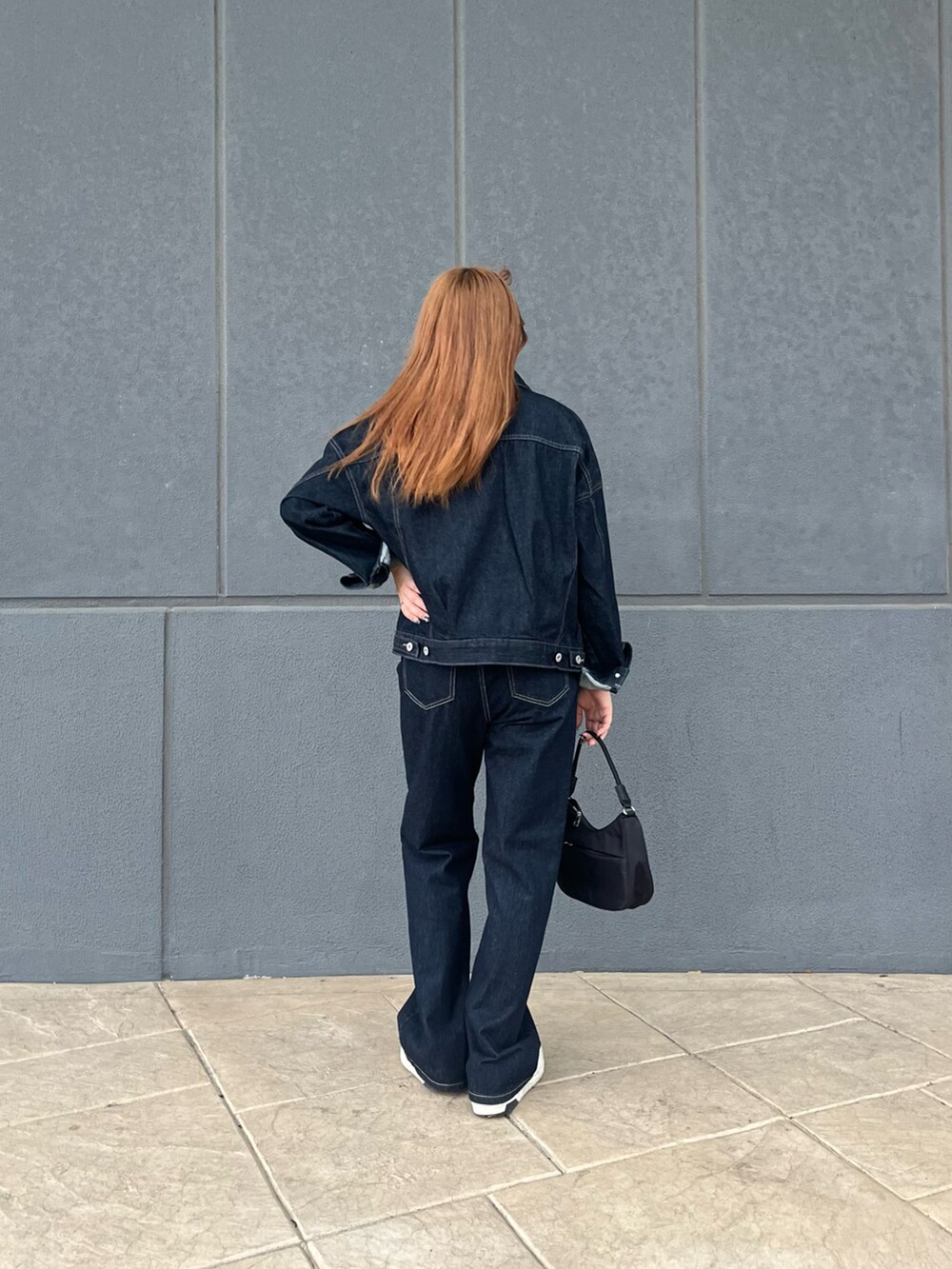 ブルー系のデニムジャケット、ブルー系のデニムパンツ、ブラック系のハンドバッグを着用したレディースの秋コーディネートの4枚目の写真