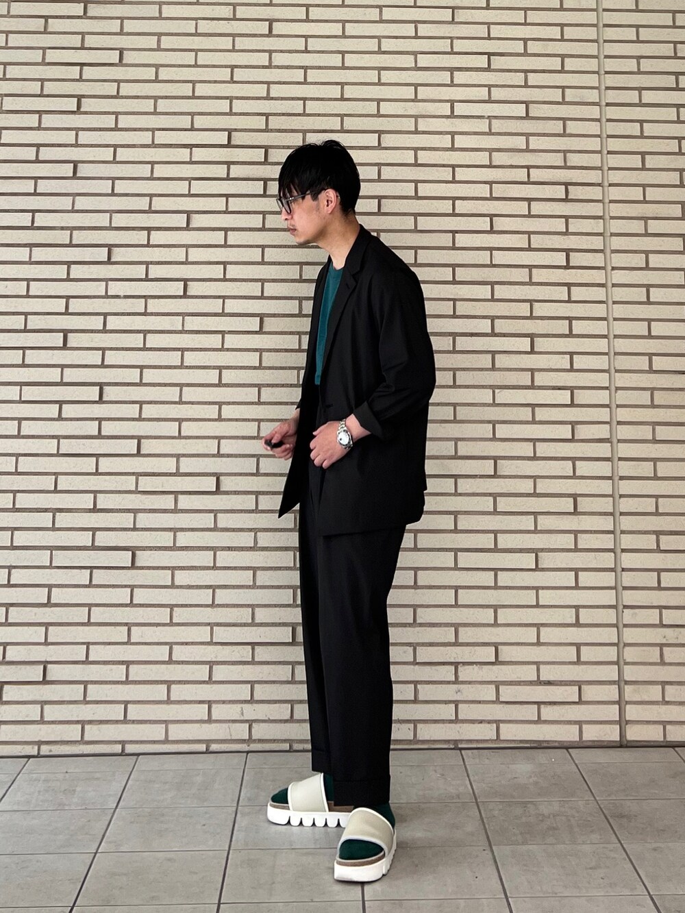グリーン系のTシャツ/カットソー、ブラック系のセットアップ、ブラック系のスラックスを着用したメンズの春コーディネートの2枚目の写真