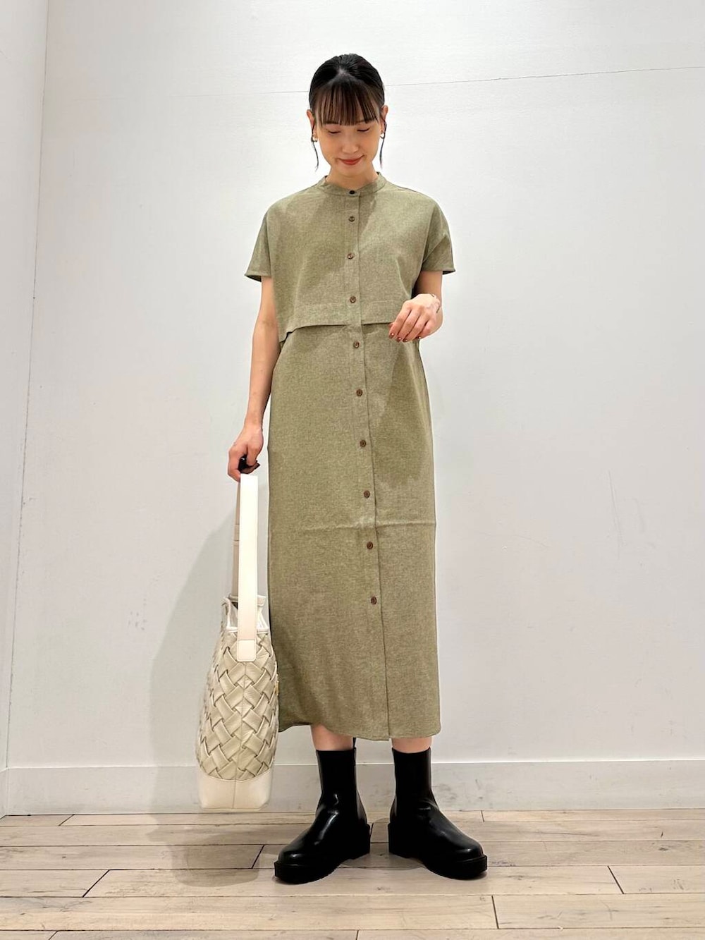 ホワイト系のトートバッグ、グリーン系のワンピース、ブラック系のブーツを着用したレディースの夏コーディネートの2枚目の写真