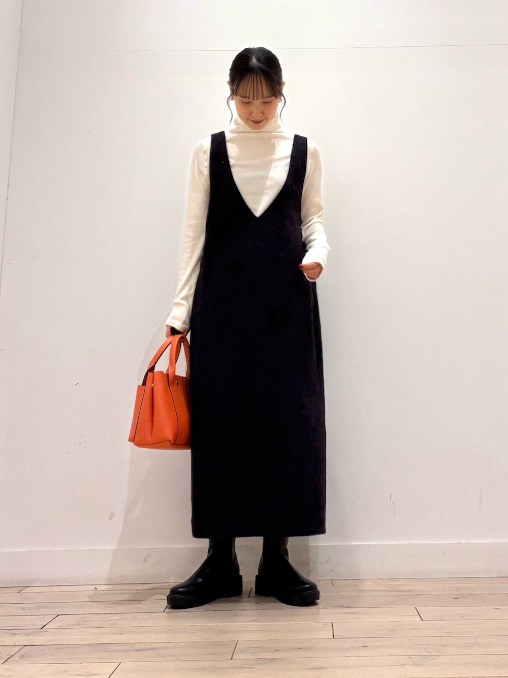 ブラック系のブーツ、オレンジ系のトートバッグ、グレー系のワンピースを着用したレディースの秋コーディネートの4枚目の写真