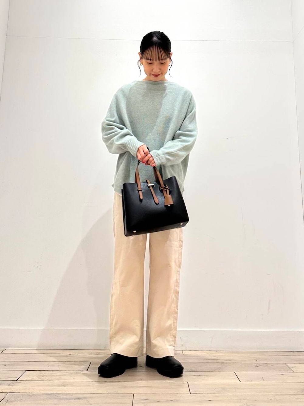 ブラック系のトートバッグ、グリーン系のニット/セーター、ブラック系のブーツを着用したレディースの冬コーディネートの2枚目の写真