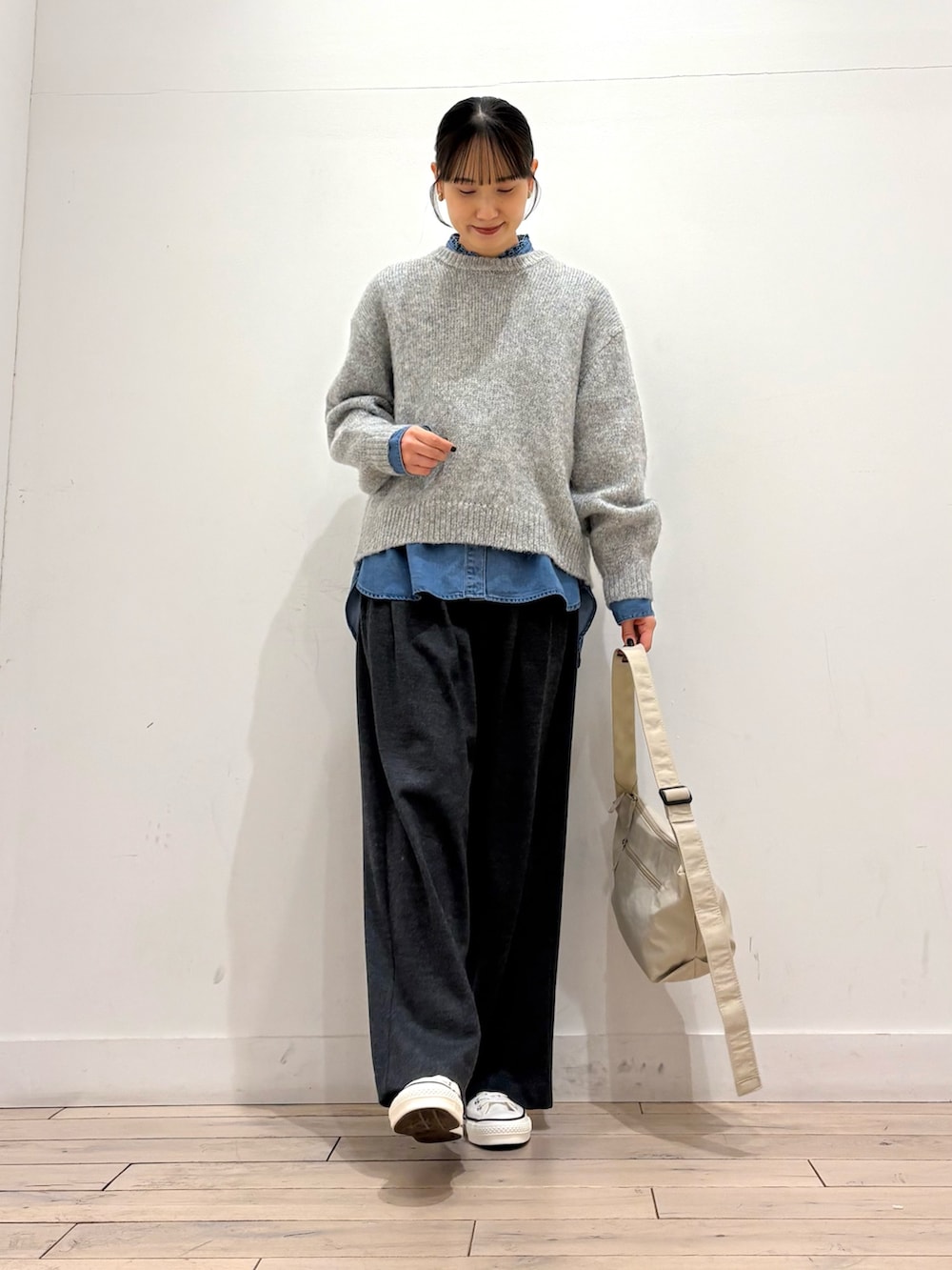 グレー系のニット/セーター、ブルー系のシャツ/ブラウス、ホワイト系のスニーカーを着用したレディースの冬コーディネートの2枚目の写真