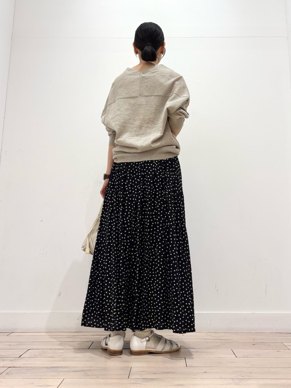 ブラック系のスカート、ホワイト系のショルダーバッグ、ホワイト系のサンダルを着用したレディースの春コーディネートの4枚目の写真