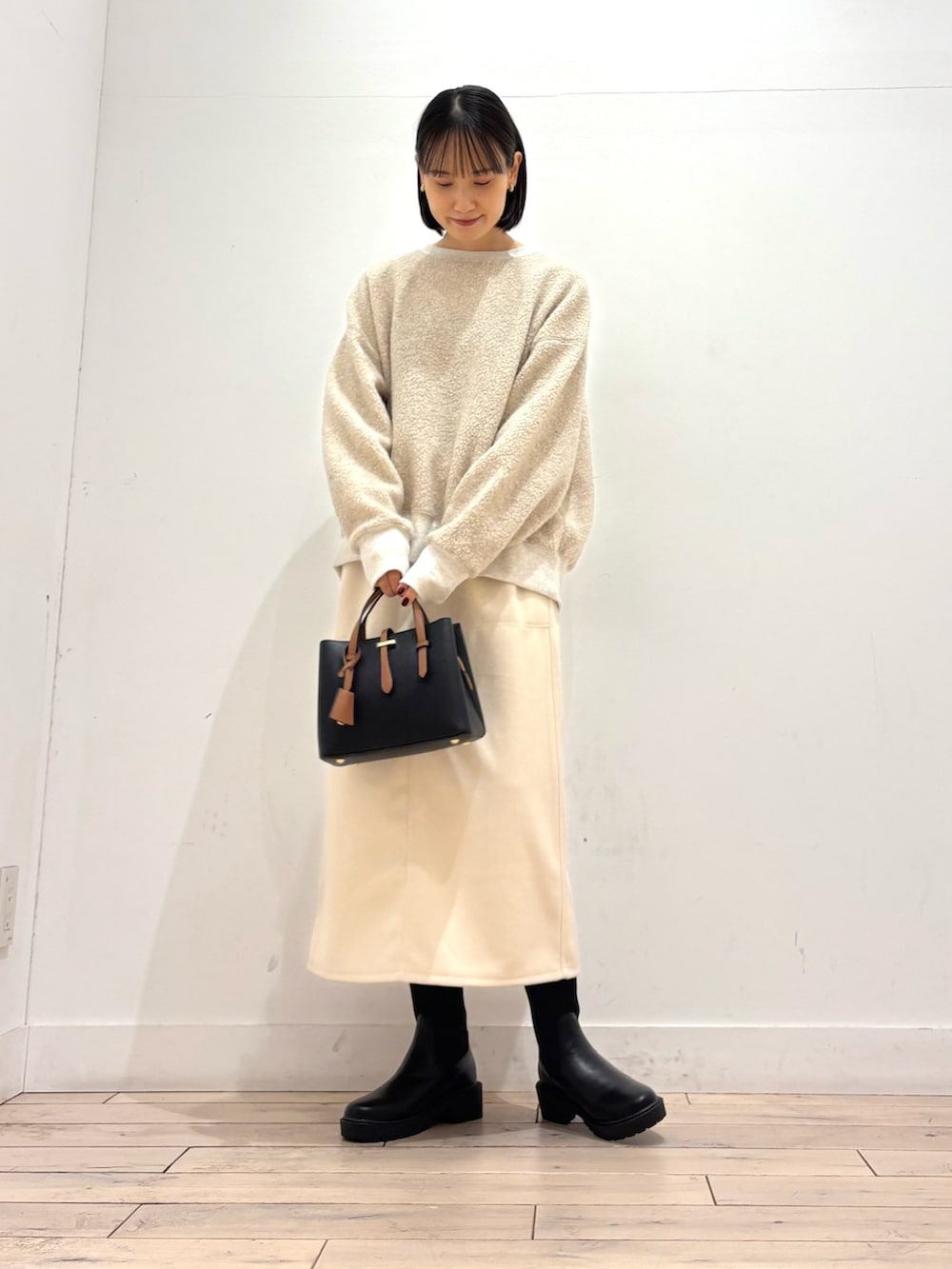 ブラック系のブーツ、ブラック系のハンドバッグ、ホワイト系のスカートを着用したレディースの冬コーディネートの4枚目の写真