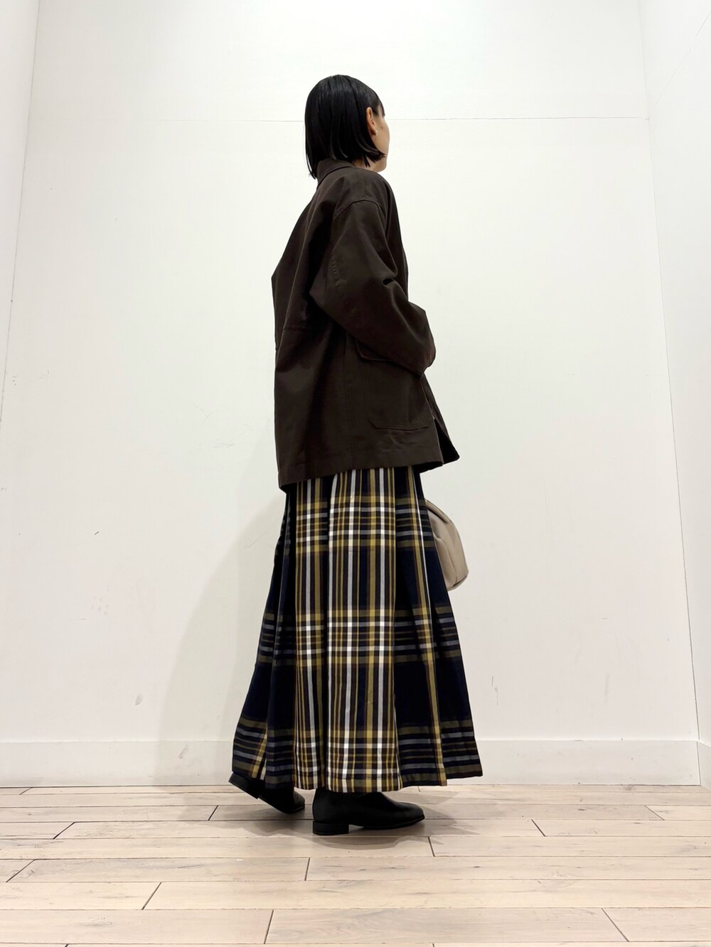 ブラウン系のカバーオール、ホワイト系のTシャツ/カットソー、ブラック系のブーツを着用したレディースの秋コーディネートの2枚目の写真