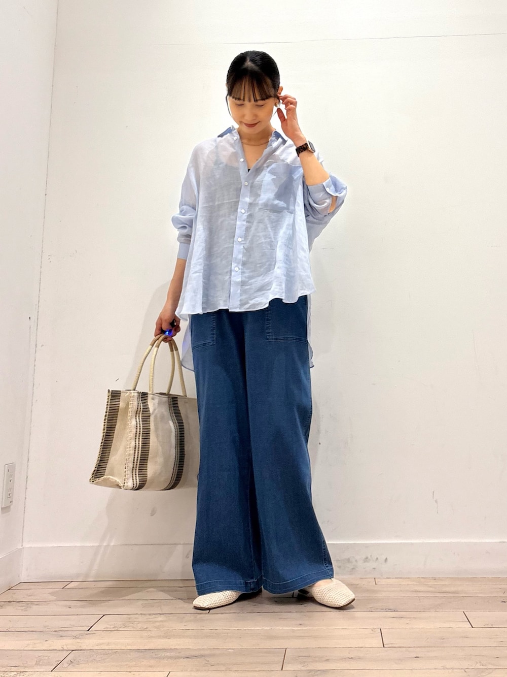 ブルー系のデニムパンツ、ホワイト系のトートバッグ、ホワイト系のバレエシューズを着用したレディースの夏コーディネートの3枚目の写真