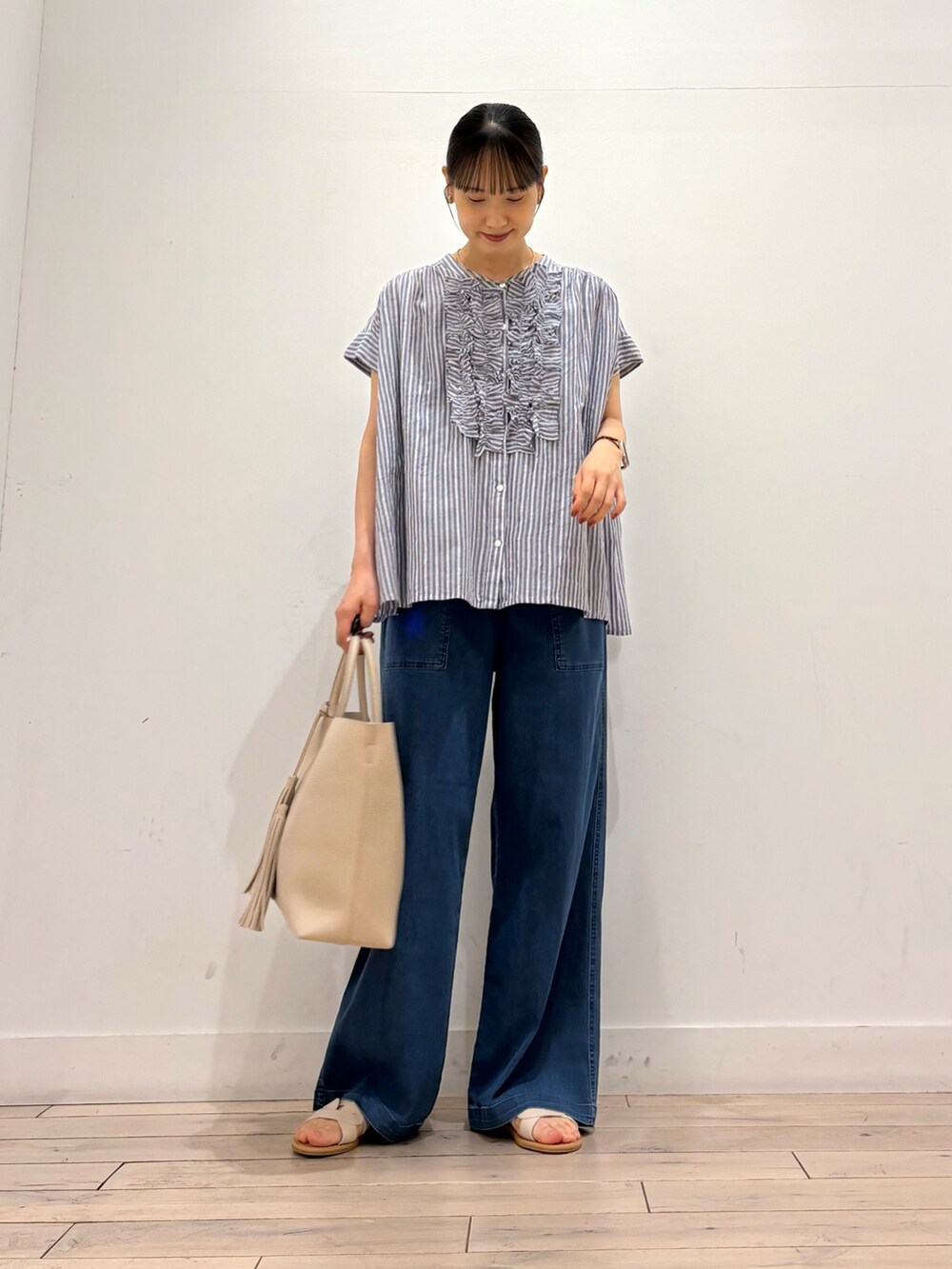ブルー系のシャツ/ブラウス、ブルー系のデニムパンツ、ホワイト系のトートバッグを着用したレディースの夏コーディネートの2枚目の写真