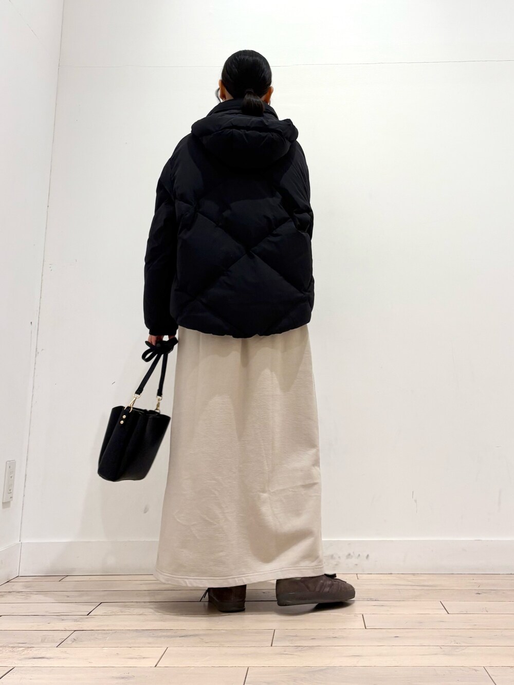 ブラウン系のニット/セーター、ブラック系のダウンジャケット/コート、ベージュ系のスカートを着用したレディースの冬コーディネートの4枚目の写真