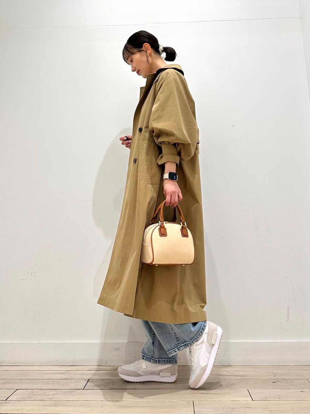 ブルー系のデニムパンツ、ベージュ系のその他アウター、イエロー系のボストンバッグを着用したレディースの冬コーディネートの3枚目の写真