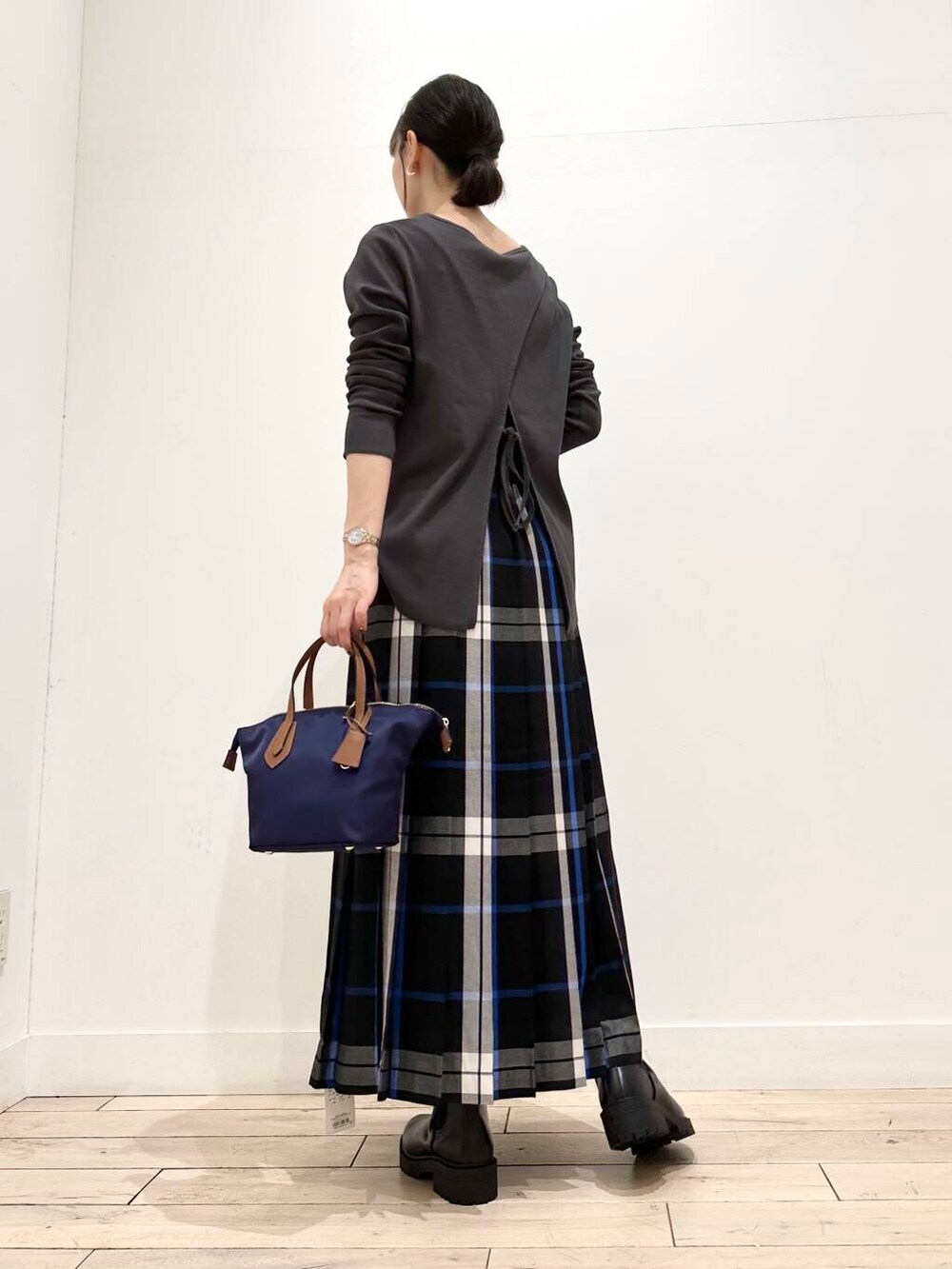 ブルー系のトートバッグ、ブラック系のブーツ、ブラック系のスカートを着用したレディースの夏コーディネートの4枚目の写真