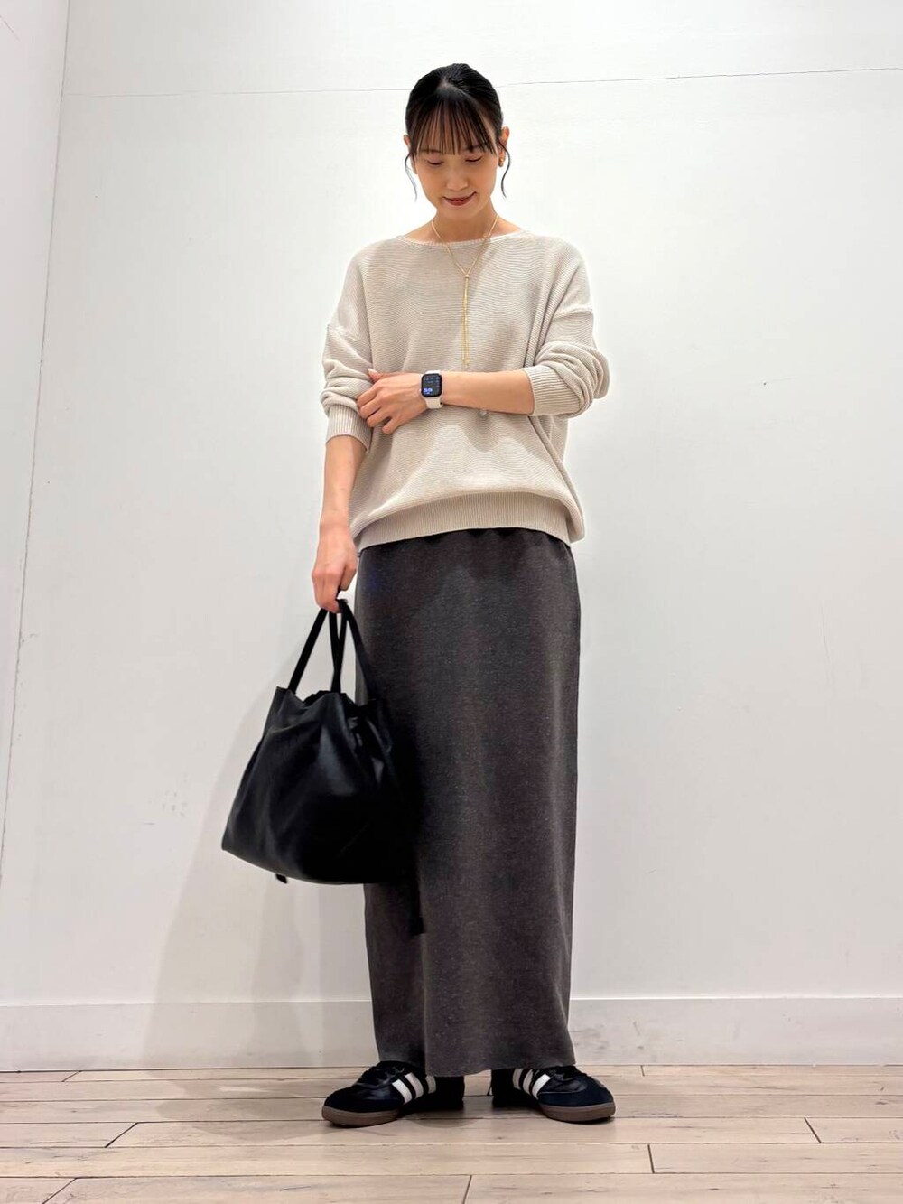 ブラック系のショルダーバッグ、グレー系のニット/セーター、グレー系のスカートを着用したレディースの春コーディネートの2枚目の写真