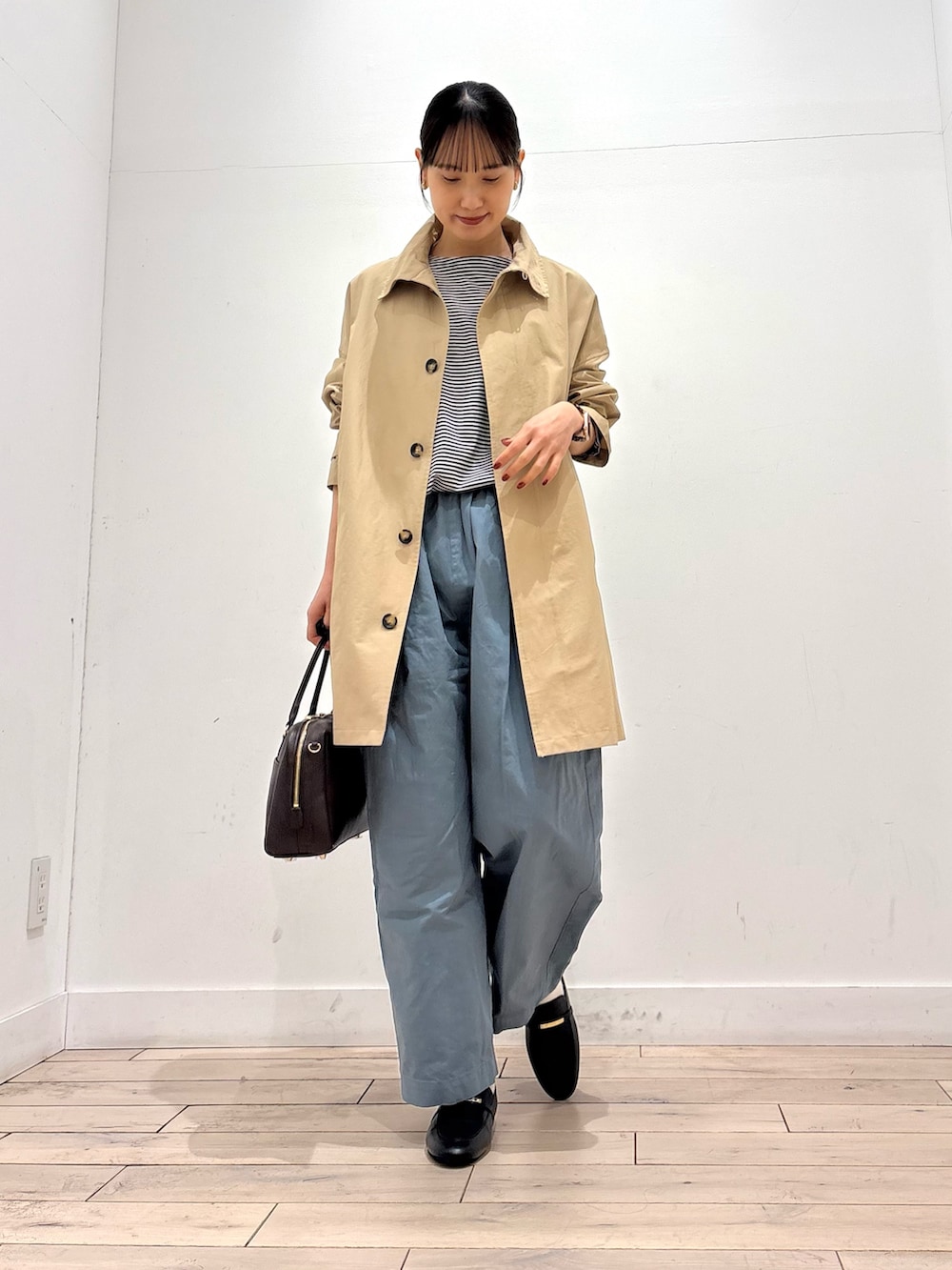 ベージュ系のステンカラーコート、ブラック系のTシャツ/カットソー、ブルー系のその他パンツを着用したレディースの春コーディネートの2枚目の写真
