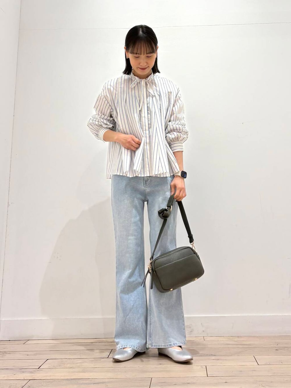 グリーン系のショルダーバッグ、シルバー系のパンプス、ブルー系のデニムパンツを着用したレディースの春コーディネートの2枚目の写真