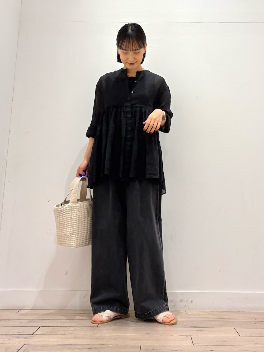 ブラック系のデニムパンツ、ホワイト系のトートバッグ、ホワイト系のサンダルを着用したレディースの春コーディネートの3枚目の写真