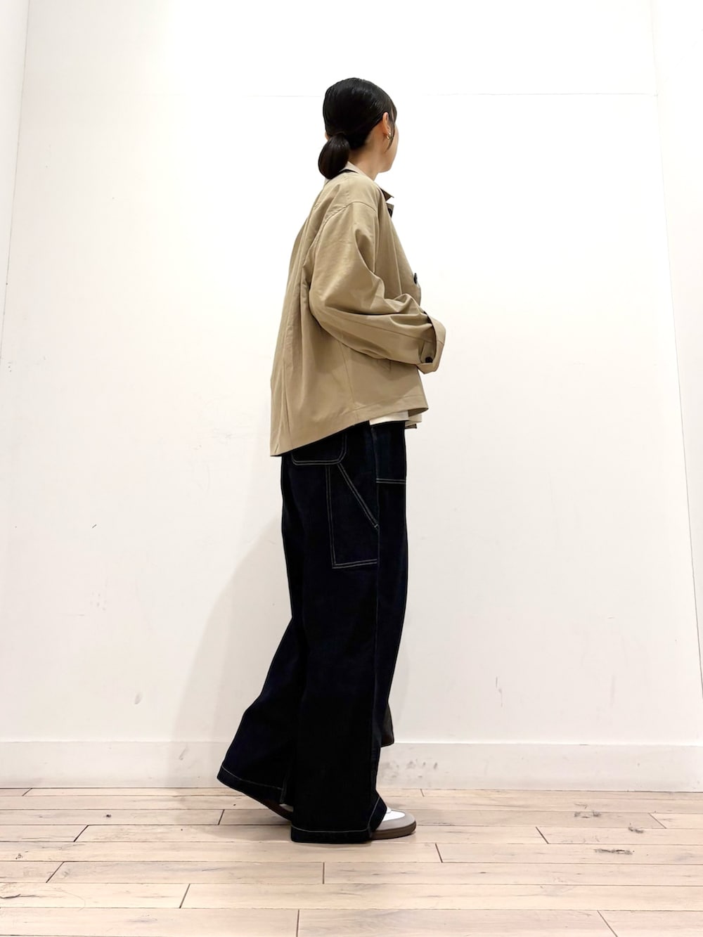 ベージュ系のステンカラーコート、ホワイト系のTシャツ/カットソー、ブルー系のデニムパンツを着用したレディースの秋コーディネートの4枚目の写真