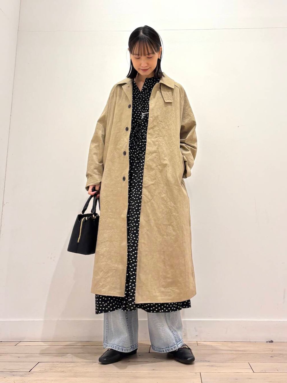 ブラック系のハンドバッグ、ブルー系のデニムパンツ、ブラック系のワンピースを着用したレディースの春コーディネートの4枚目の写真