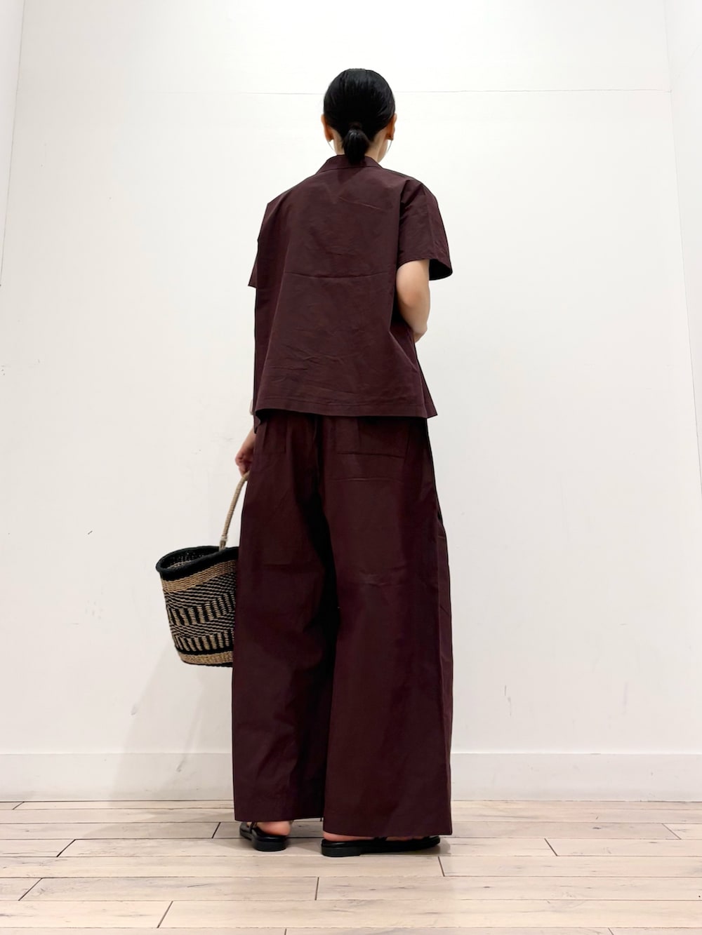ブラウン系のその他パンツ、ブラック系のかごバッグ、ブラック系のサンダルを着用したレディースの夏コーディネートの3枚目の写真