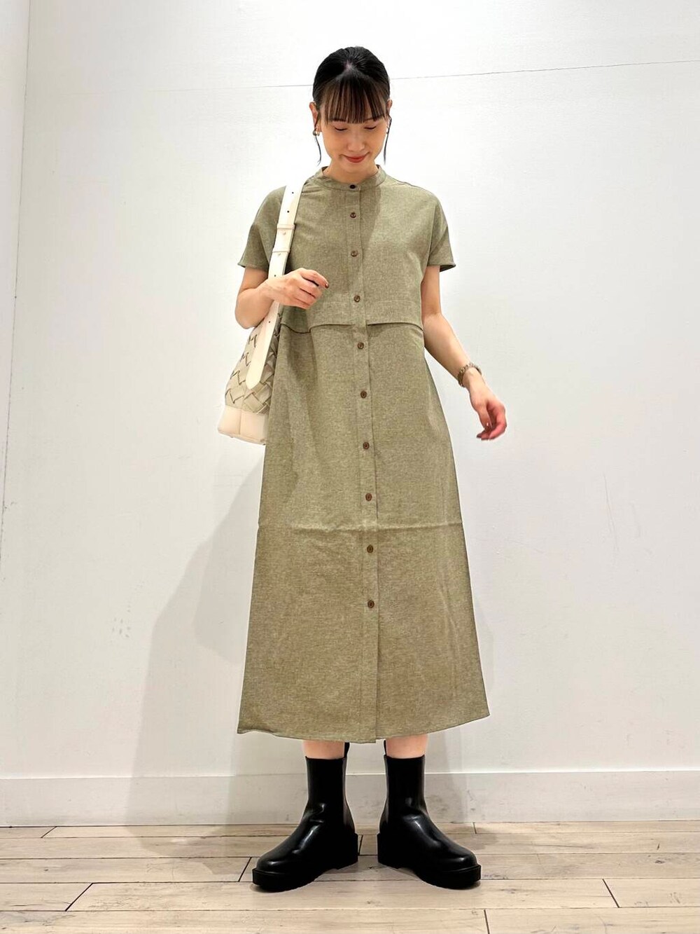 ホワイト系のトートバッグ、グリーン系のワンピース、ブラック系のブーツを着用したレディースの夏コーディネートの3枚目の写真