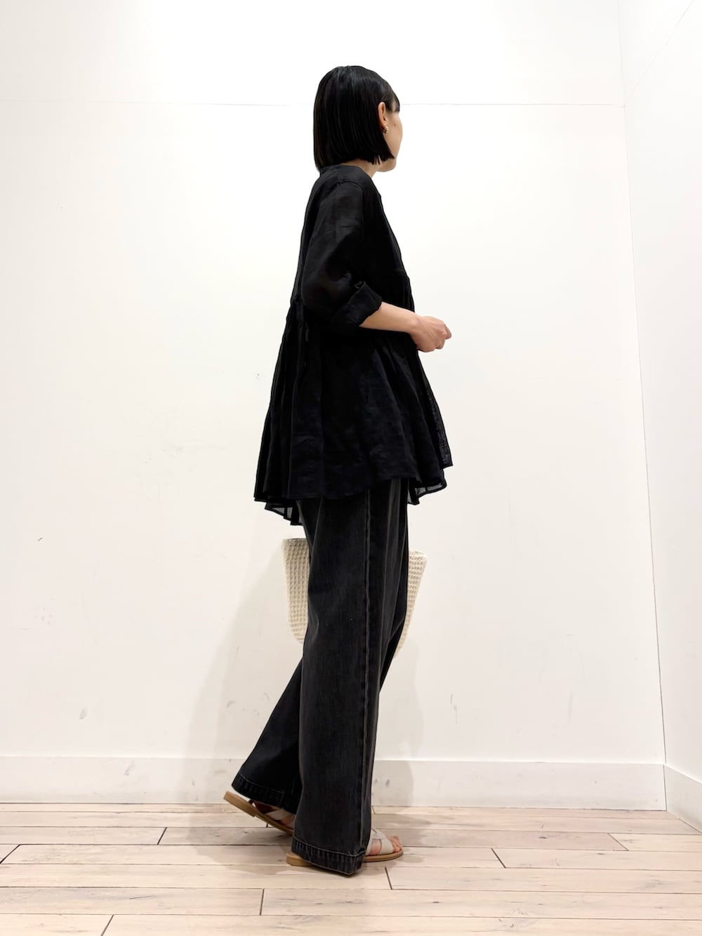ブラック系のデニムパンツ、ホワイト系のトートバッグ、ホワイト系のサンダルを着用したレディースの春コーディネートの5枚目の写真