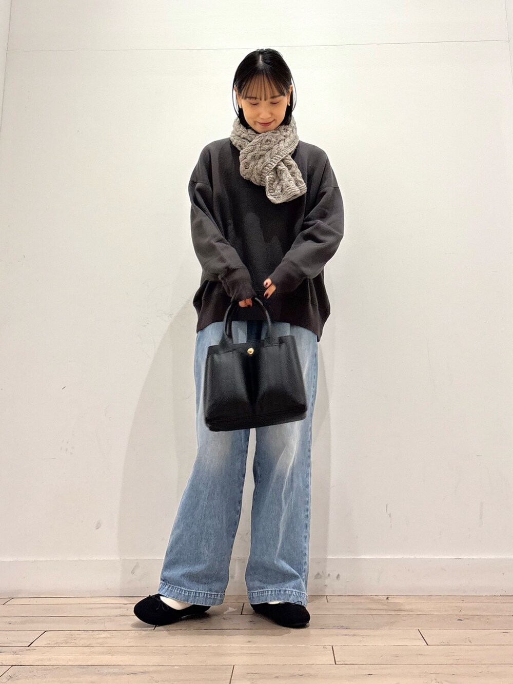 グレー系のスウェット、ブルー系のデニムパンツ、ブラック系のトートバッグを着用したレディースの冬コーディネートの2枚目の写真