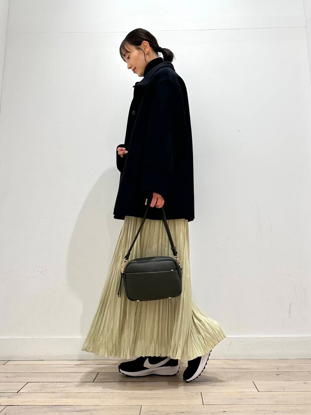 グリーン系のショルダーバッグ、ブラック系のその他アウター、ブラック系のニット/セーターを着用したレディースの冬コーディネートの2枚目の写真