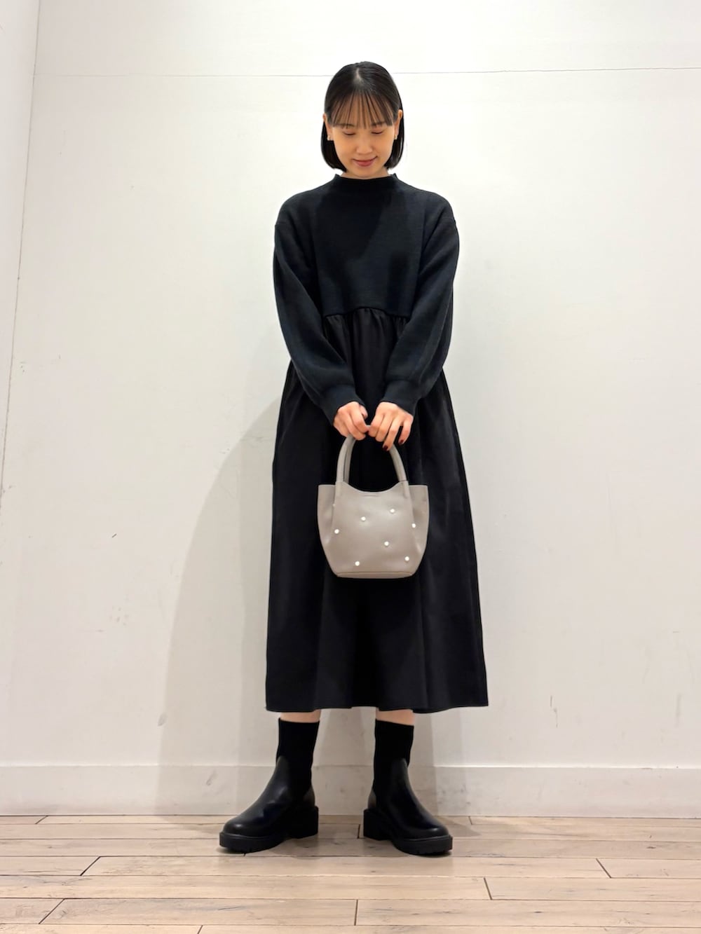 ブラック系のワンピース、グレー系のハンドバッグ、ブラック系のブーツを着用したレディースの秋コーディネートの3枚目の写真