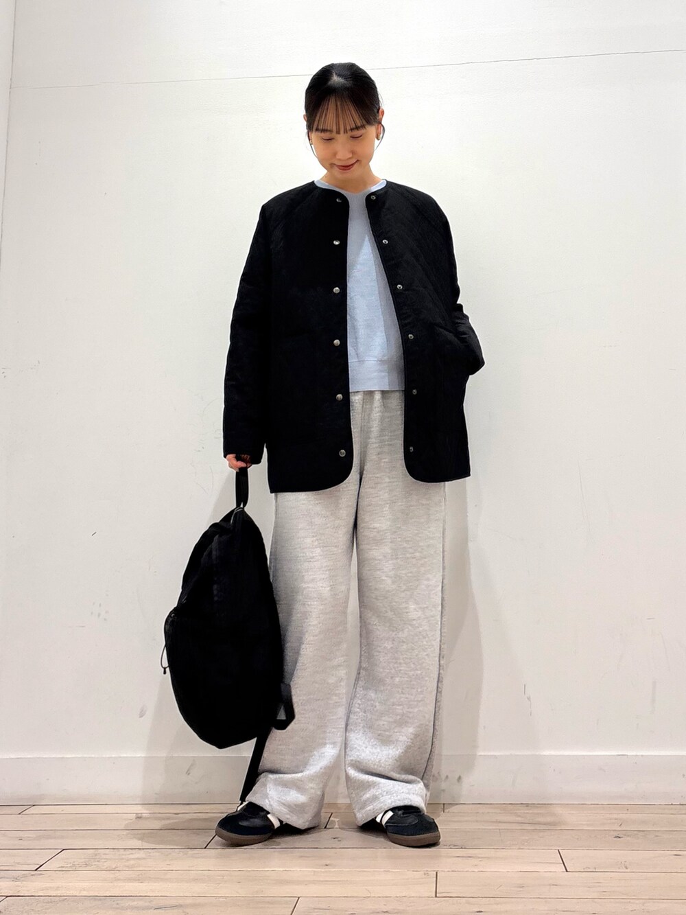 ブルー系のニット/セーター、ブラック系のダウンジャケット/コート、グレー系のその他パンツを着用したレディースの春コーディネートの2枚目の写真